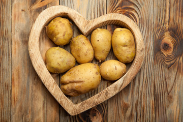 Plakat Bunch of potatoes on wooden background close up shoot
