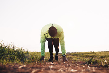 Strong male runner in start pose on outdoors. Morning workout training