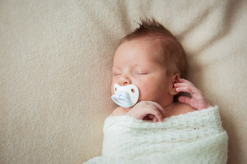 Cute newborn baby sleeping on white blanket with a pacifier © irena_geo