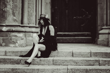 Gothic lady in a luxurious glamorous retro look for Halloween. Beautiful citizen in vintage clothing with feathers and fine accessories of handmade work. Ideas for the  Halloween holiday