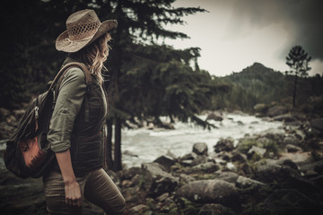 Beautiful woman hiker near wild mountain river.