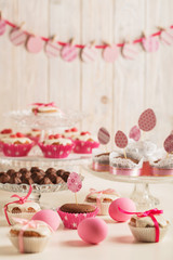 Easter cupcakes decorated with pink candy, paper eggs and ribbons.
