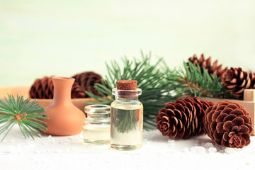 Essential oil in bottle, surrounded cones and pine boughs, natural wintertime aromatherapy treatment. 