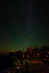 The Milky Way in night sky with stars and some trees.