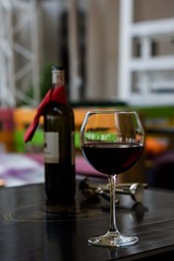 Glass of red wine with bottle and corkscrew on table in cafe