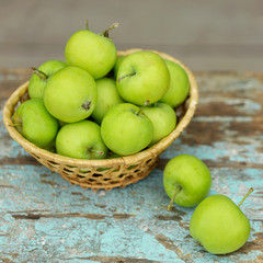 Homemade rustic green apples in a basket on an old stool.