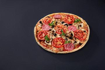 Food ingredients and spices for cooking and delicious italian pizza on black concrete background.