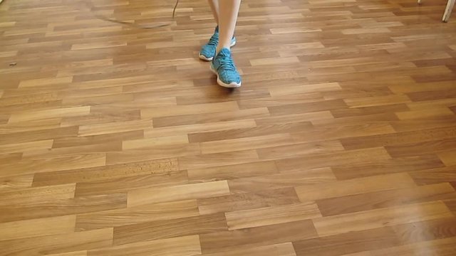 Sporty woman's legs in blue sneakers jump rope - 33s. The girl walks into the frame, jumps rope and off out, video without sound can be looped