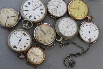 Old pocket watches lie on a gray table in the market. Old hours for collectors.