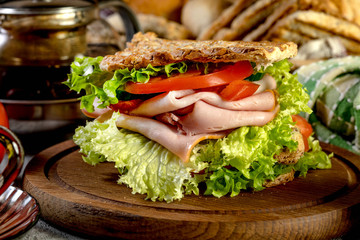 Sandwich with ham, cucumber, tomato and lettuce.