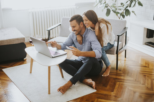 Cheerful Couple Searching Internet On Laptop At Home