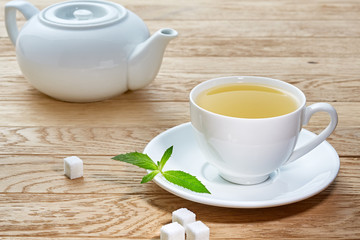 cup with green tea and teapot on white wooden table background.