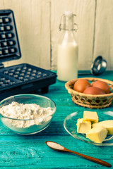 Making waffles at home - waffle iron and ingredients - milk, eggs and flour.