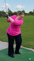 Golfspielerin beim Abschlag auf einem Golfplatz
