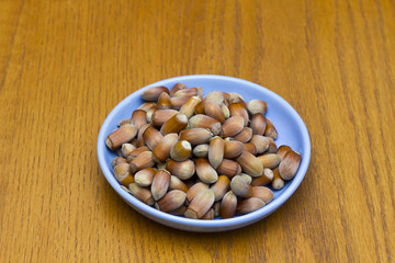 Full bowl of hazelnuts in a brown bowl, top view