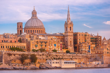 Obraz premium Valletta Skyline with ship at beautiful sunset from Sliema with churches of Our Lady of Mount Carmel and St. Paul's Anglican Pro-Cathedral, Valletta, Capital city of Malta