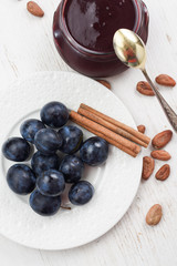 Raw organic plums, jam, raw cocoa beans and cinnamon on white background