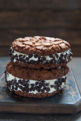 Homemade vanilla ice cream sandwiches with chocolate drops cookies on dark background