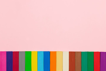 Sticks of colorful plasticine on pastel pink background