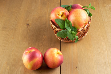 peaches in a wicker basket on wooden table with blurred background