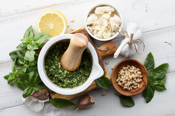Basil pesto sauce with main ingredients: fresh basil leaves, parmesan cheese, pine nuts, garlic and lemon