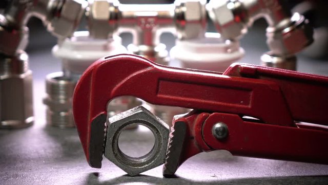 Red metalwork adjustable spanner for sanitary works against the background of Water shutoff and connecting shutoff valves for water supply