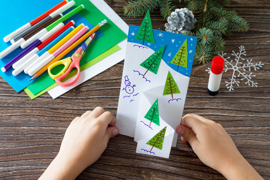 The child makes a greeting card Christmas. Made with his own hands. Children's art project craft for kids. Craft for children.