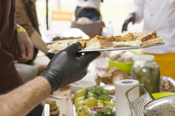 Male in black rubber gloves holds plate of bread