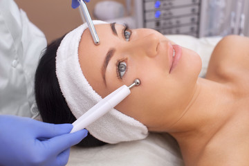 The cosmetologist makes the apparatus a procedure of Microcurrent therapy of a beautiful, young...