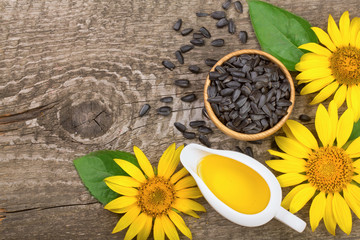 Sunflower oil, seeds and flower on wooden background with copy space for your text. Top view