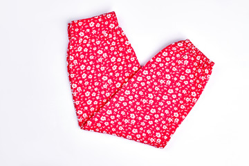 Baby-girl red cotton pants. Toddler girls new folded trousers with a pattern of small white flowers, isolated on white background.