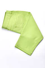 Baby-girl new colored jeans. Infant girl light green cotton pants folded on white background, top view.