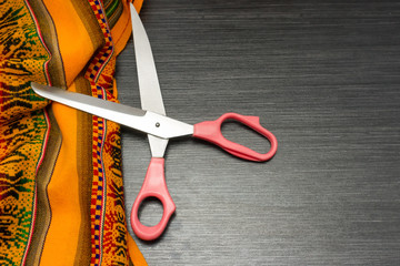 Multicolor pattern cloth with tailoring scissors on wooden table for background. Fabric texture. Wooden texture.Template for designers