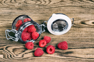 Decorative detail of spilled raspberries on a wooden background. Delicious juicy refreshment on garden table.