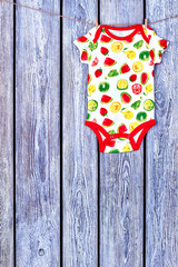 Obraz premium Baby soft bodysuit hanging on clothesline. Rope with drying newborn girl romper on wooden background, copy space.