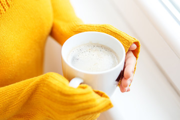 The cup of hot coffee with milk in your hands. Beverage concept, lifestyle, autumn and winter.