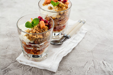 Layered dessert with granola, apple and red bilberry compote, cream