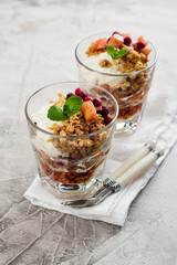 Layered dessert with granola, apple and red bilberry compote, cream