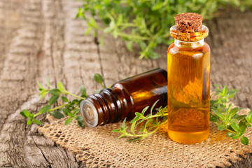 Bottle of essential oil with herbs thyme on an old wooden background