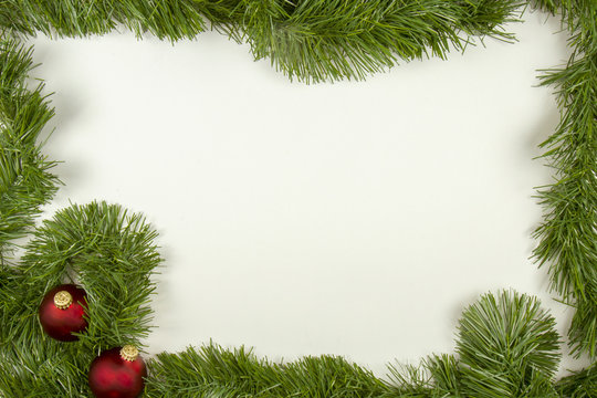 Green garland with red ornaments in frame on white
