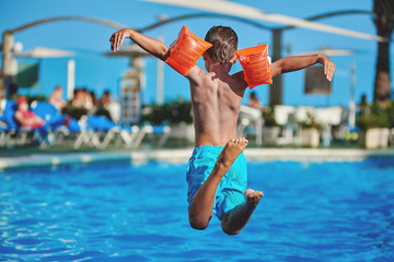 European child having fun jumping into the pool. - 171088095