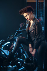 Fototapeta na wymiar beautiful young girl in black clothes is standing near a brutal motorcycle