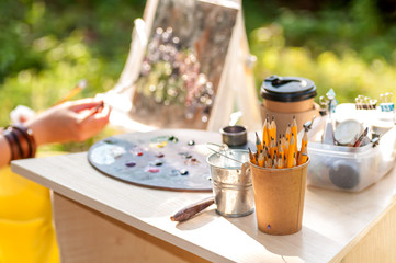 pencils in a paper cup on the table, in the background the artist draws a picture