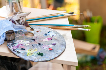 Brushes for painting dirty in paint lie on a palette with paint