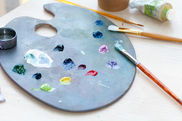 Brushes for painting dirty in paint lie on a palette with paint