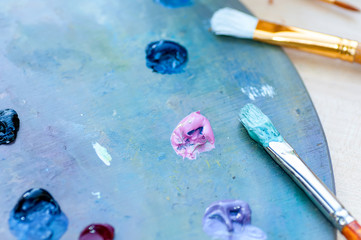 Brushes for painting dirty in paint lie on a palette with paint