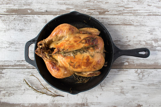 top view of baked chicken in cast iron skillet with rosemary