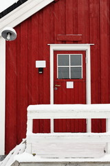 Tourist rorbuer-traditional seasonal cottages-gangplank with fence under snowfall. Hamnoy-Reine-Moskenesoya-Lofoten-Norway. 0385-2