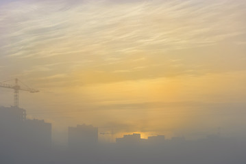 Cranes over new buildings in the early foggy morning.