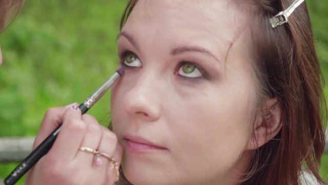 Make up artist applies shades on girl's eyelid before photoshoot